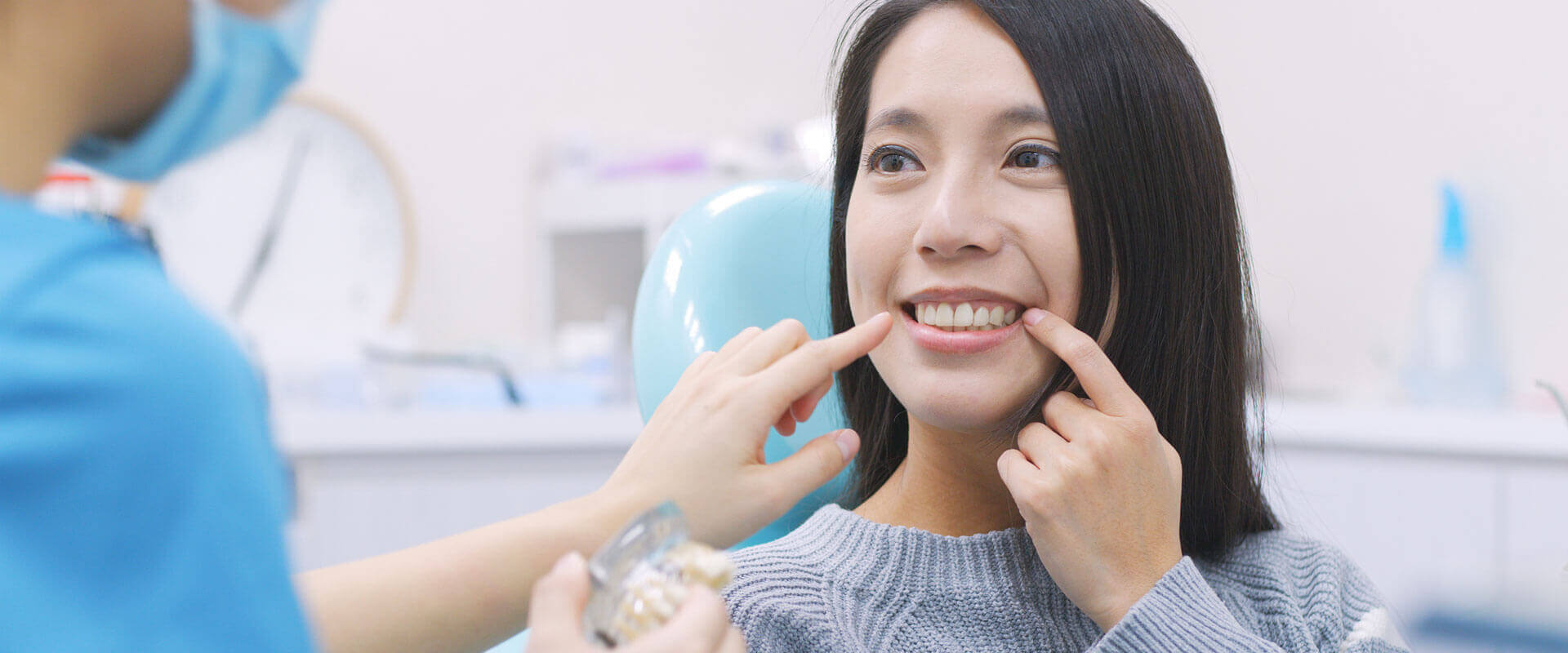 Smiling young woman pointing her finger at dental implants